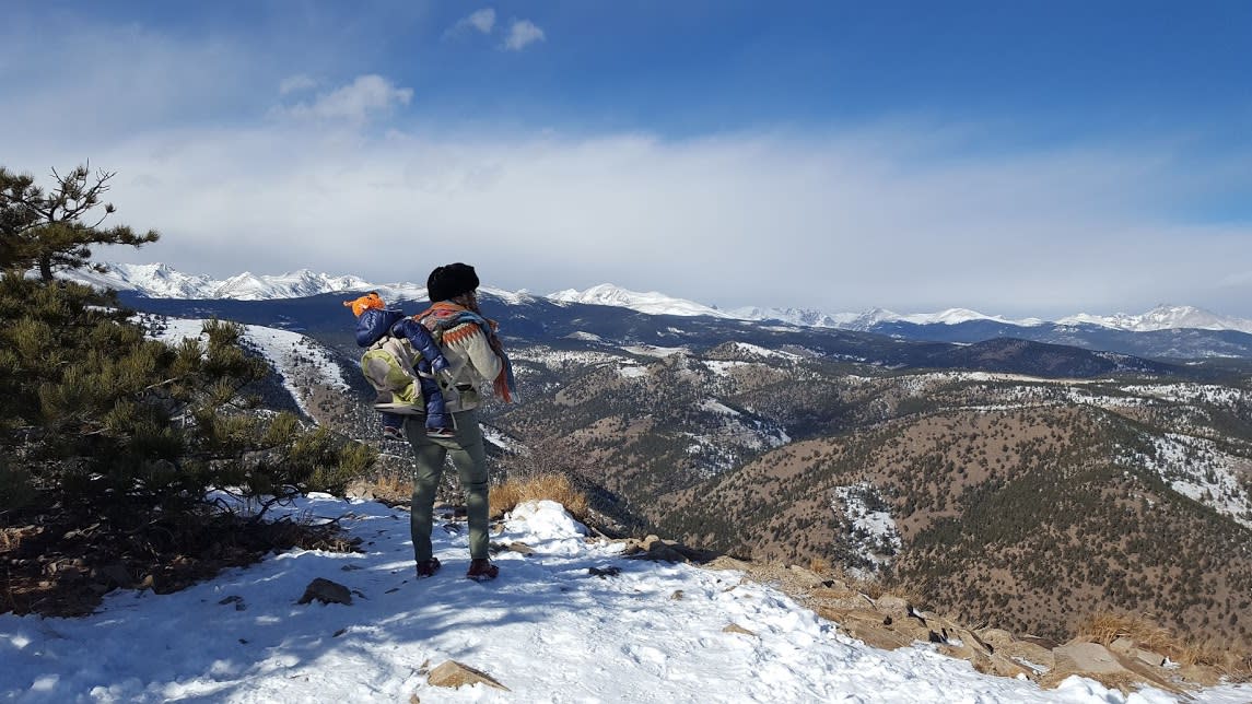 Hiker with a baby backpack overlooking the Boulder valley in the Winter