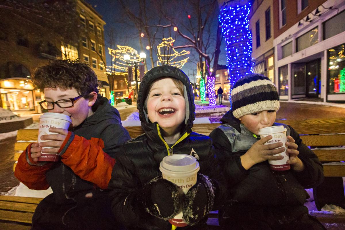 Kids sitting on bench drinking hot chocolate in downtown Boulder