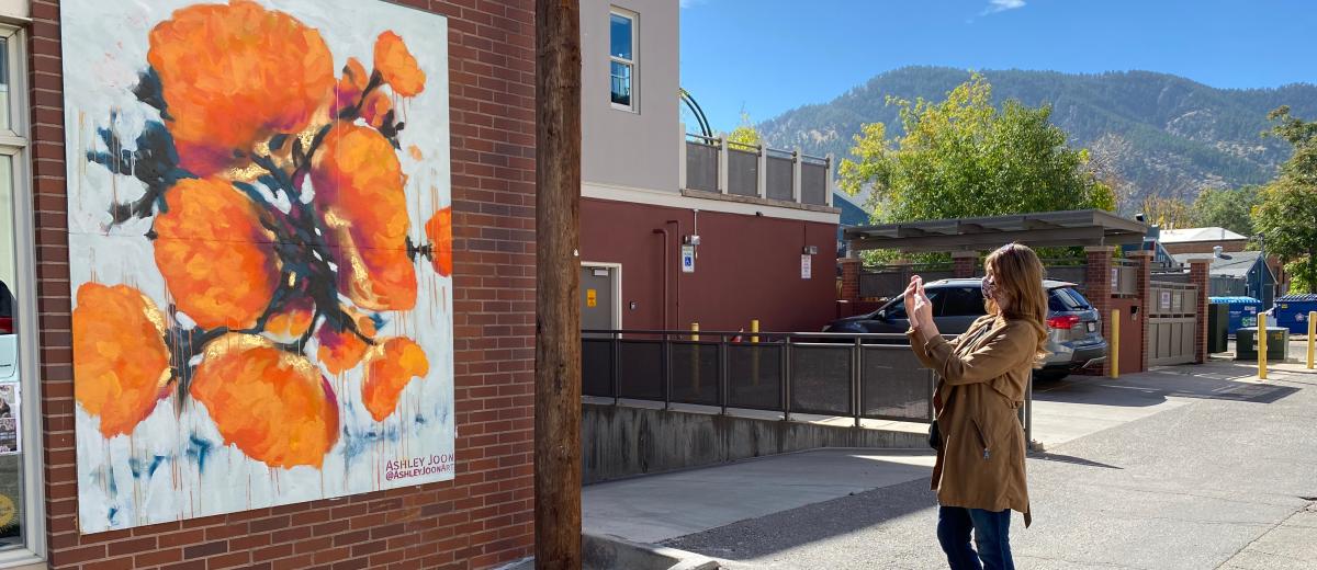A visitor snaps a quick picture of this bright Ashley Joon Mural in Boulder.