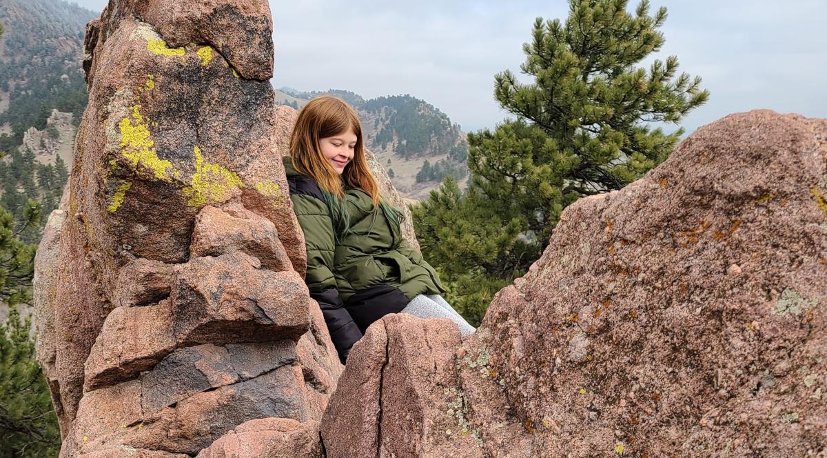 A young hiker relaxes on some large boulders along Red Rocks Trail just outside of Boulder.