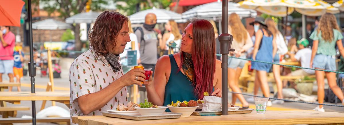 Man and woman cheers on outdoor patio in Downtown Boulder