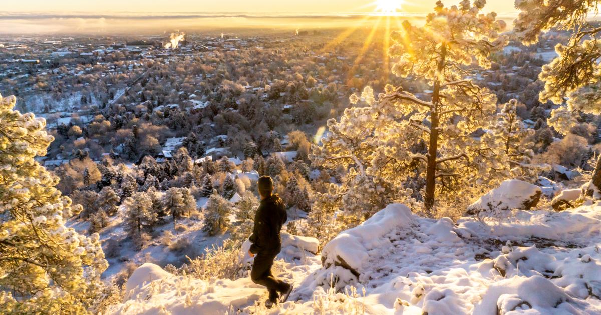 Woman hiker overlooking the valley covered in snow with sunshine