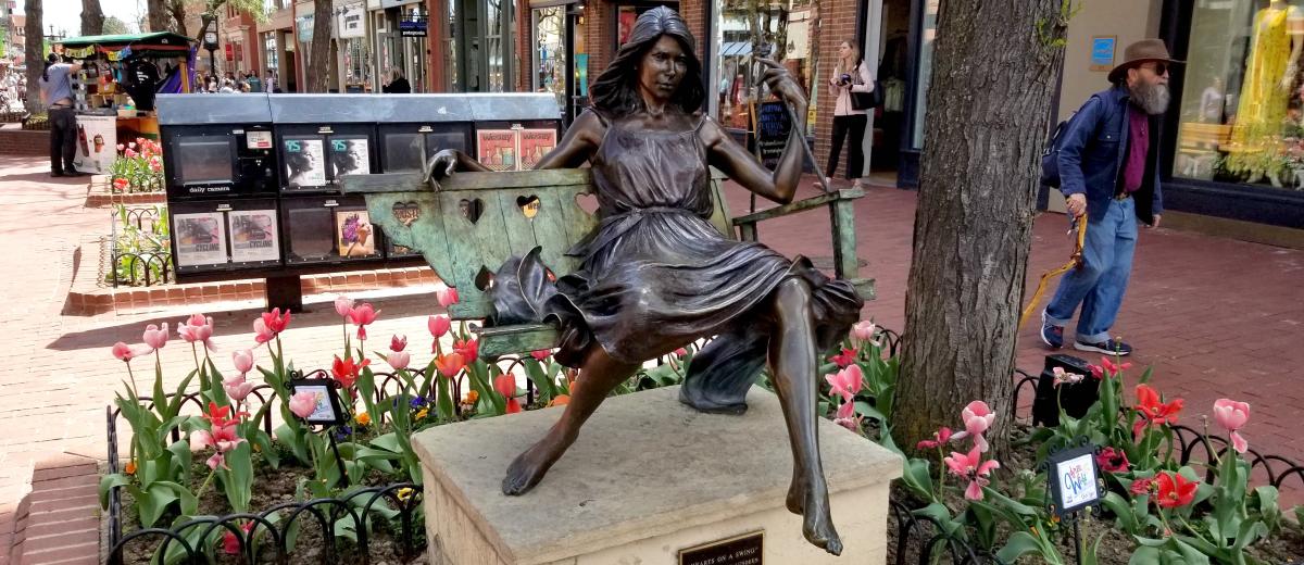 Statue in Downtown Boulder of woman on a swing